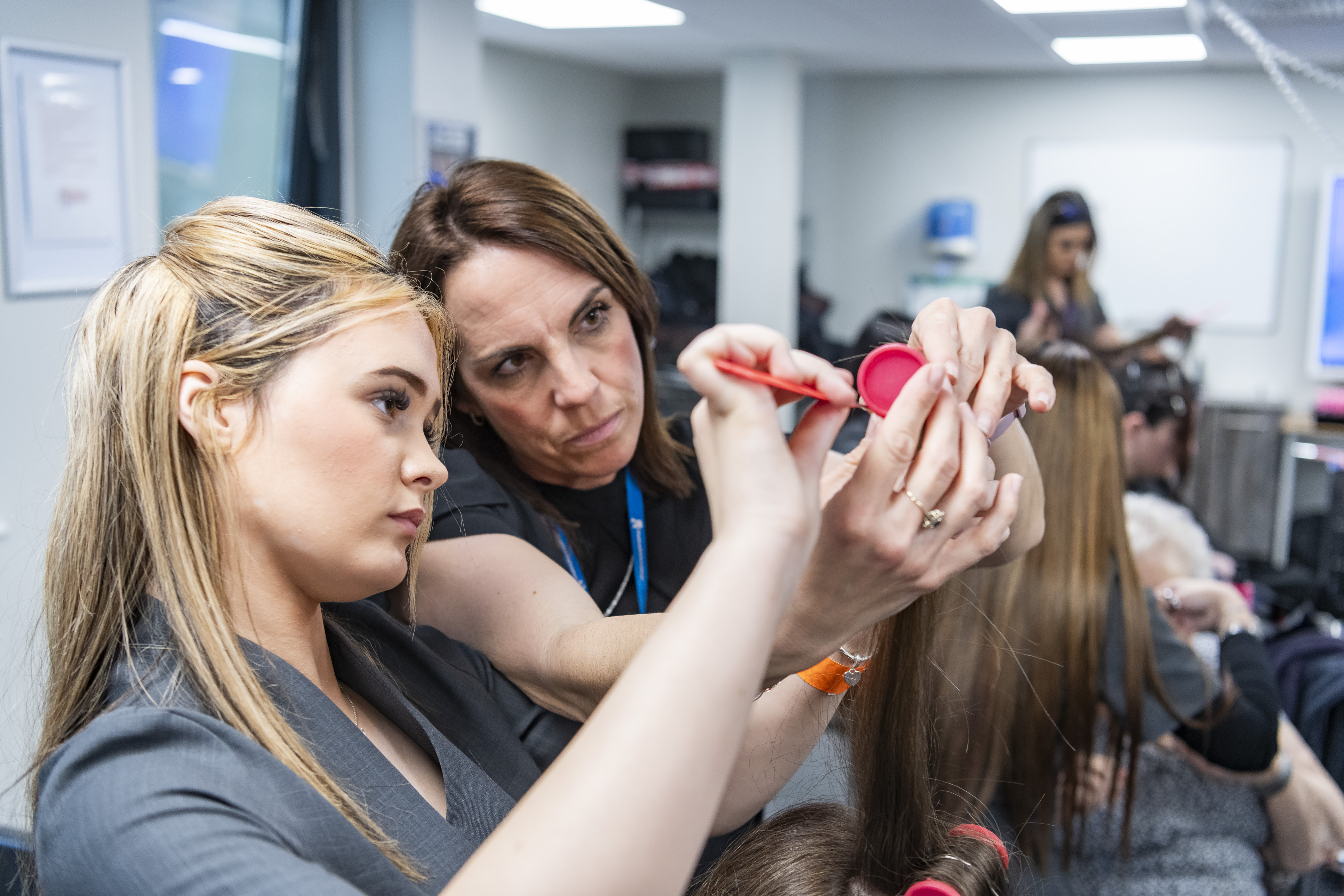 A hairdressing student styling hair in a college salon